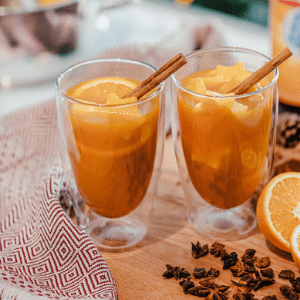 Orangenpunsch verziert mit Orangen und Zimt in einem Glas mit Servierten und Nelken