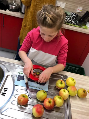 Ein Mädchen schneidet Äpfel in einer Küche